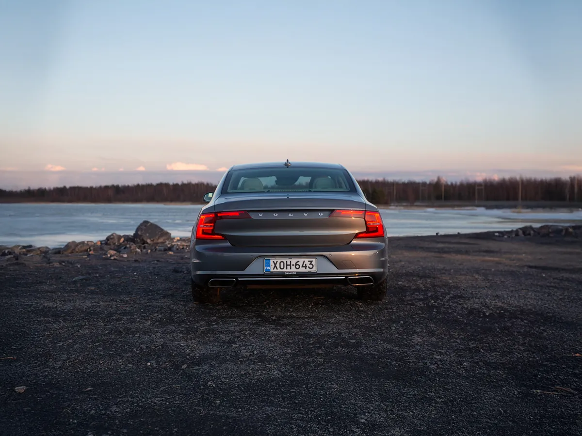 Volvo S90 takaapäin kuvattuna meren rannalla auringonlaskussa